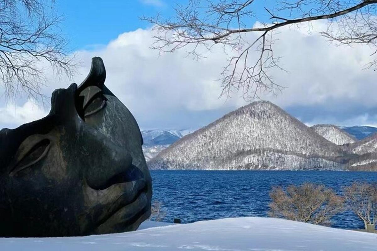 a statue of a face in the snow next to a body of water