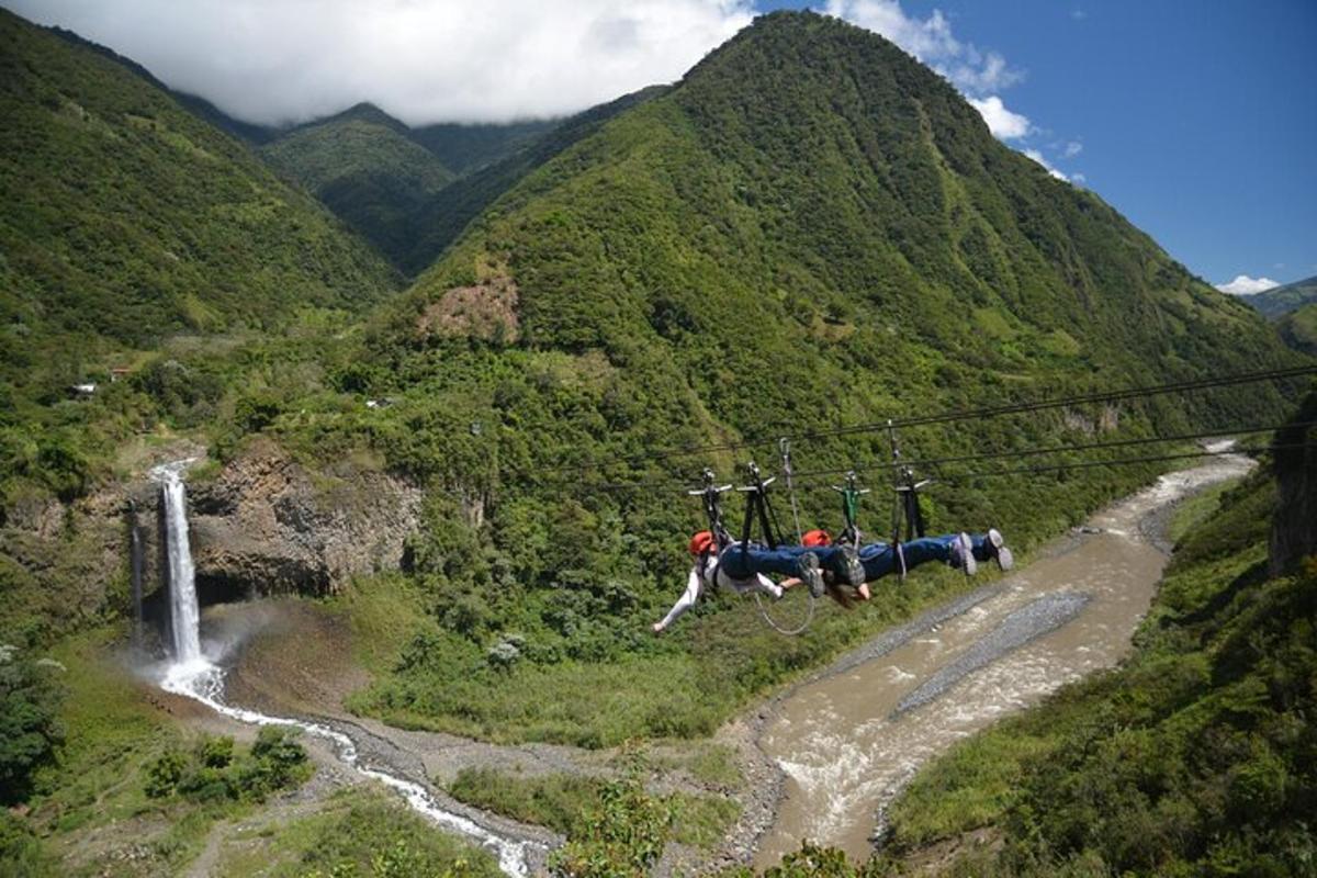 two people on a zip line over a mountain valley