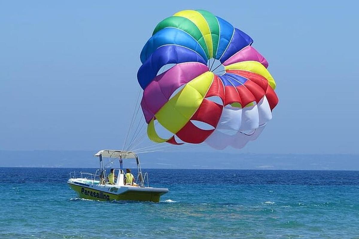 o parașută colorată zburând deasupra unei bărci în ocean