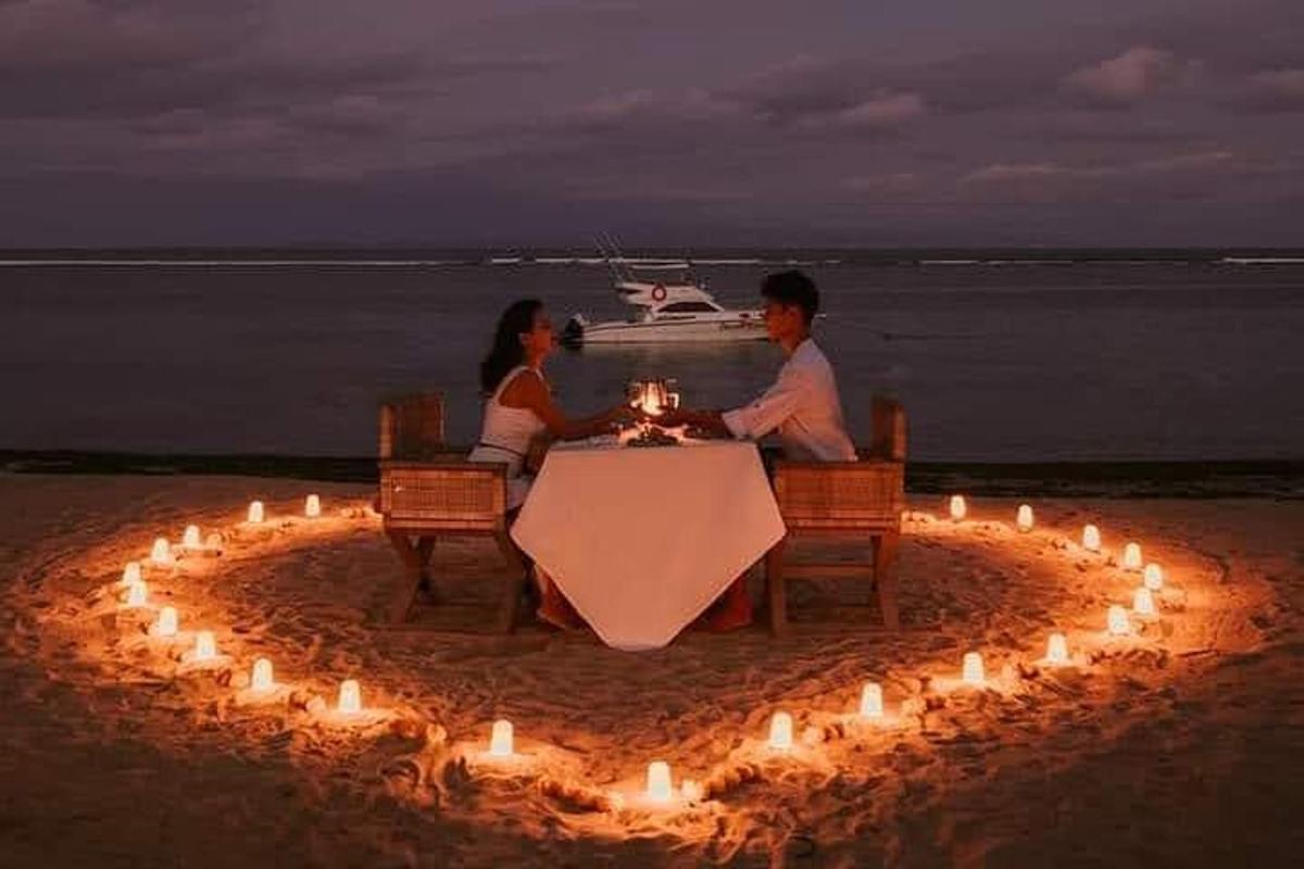 hai người ngồi ở một cái bàn có đèn trên bãi biển