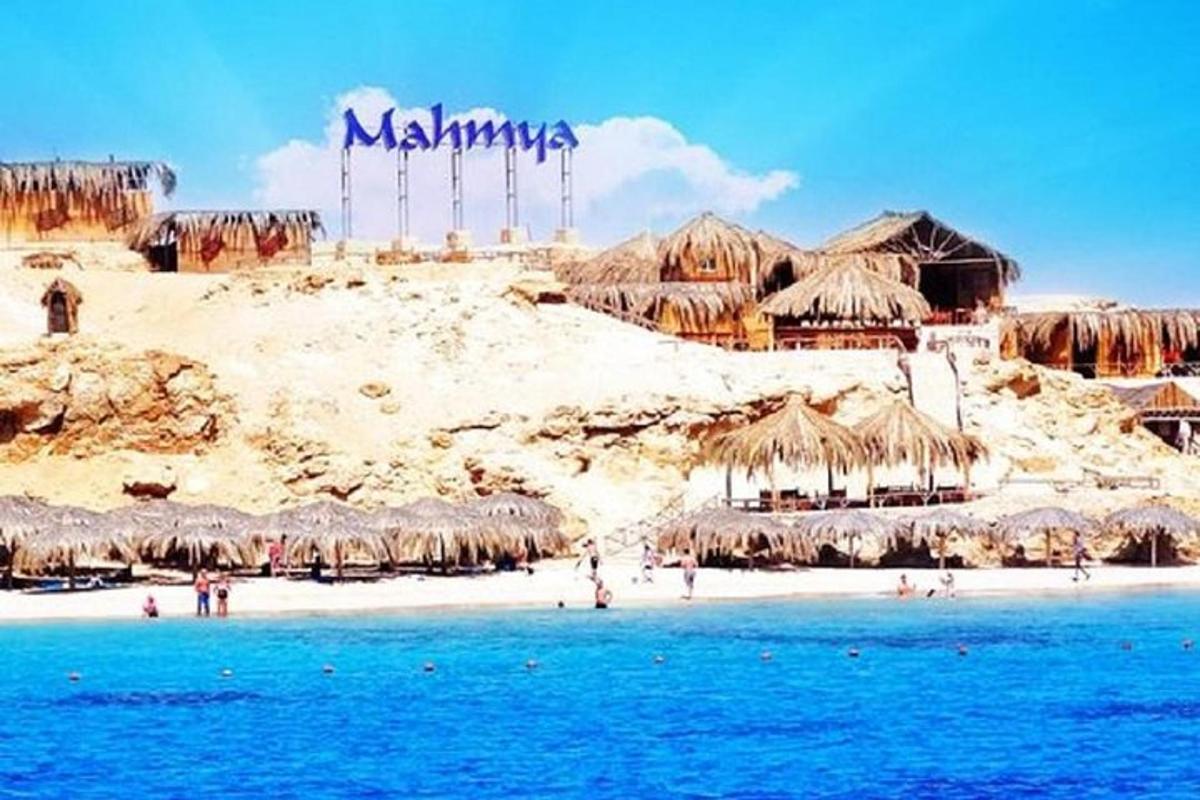 una spiaggia con ombrelloni di paglia e gente sulla spiaggia