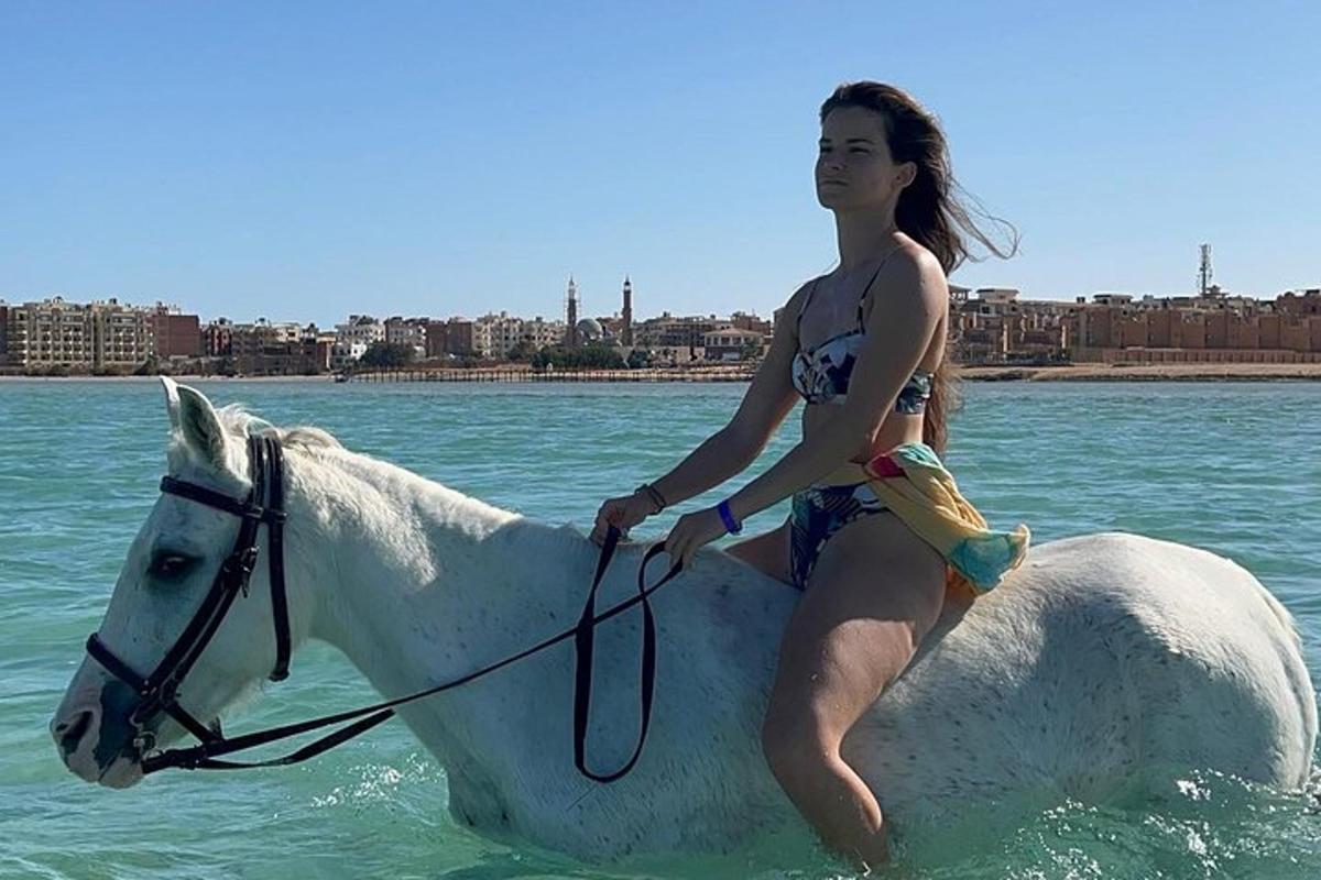 žena jedoucí na bílém koni ve vodě