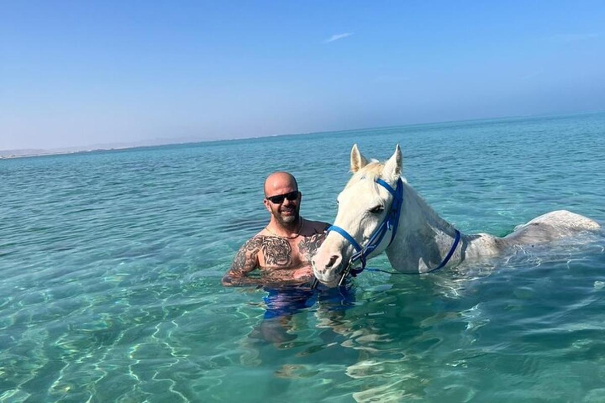 muž ve vodě s koněm v oceánu