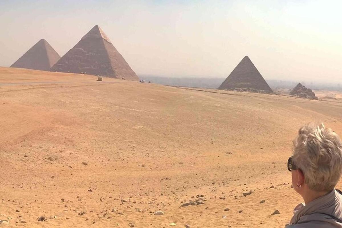 امرأة تقف أمام الأهرامات في الصحراء