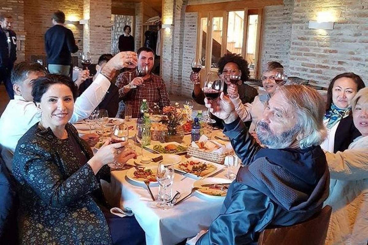 skupina lidí sedících kolem stolu a popíjejících víno