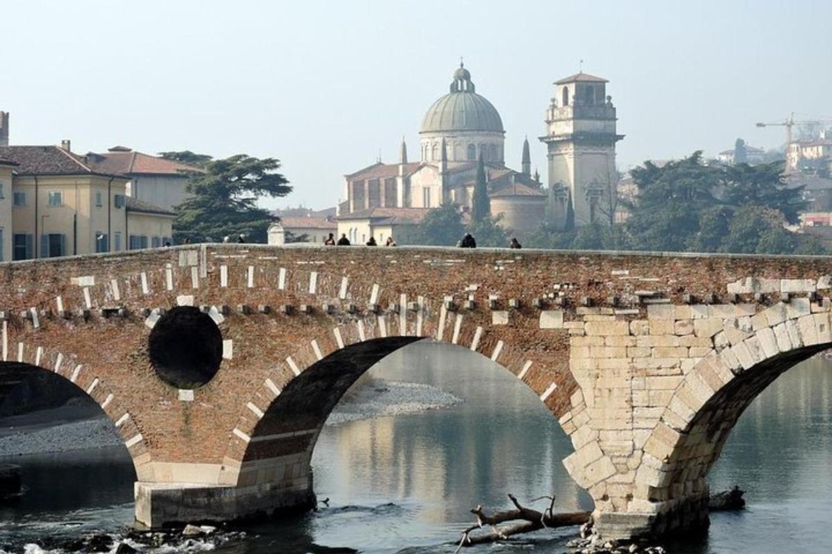 isang brick bridge sa ibabaw ng isang ilog na may mga gusali sa background
