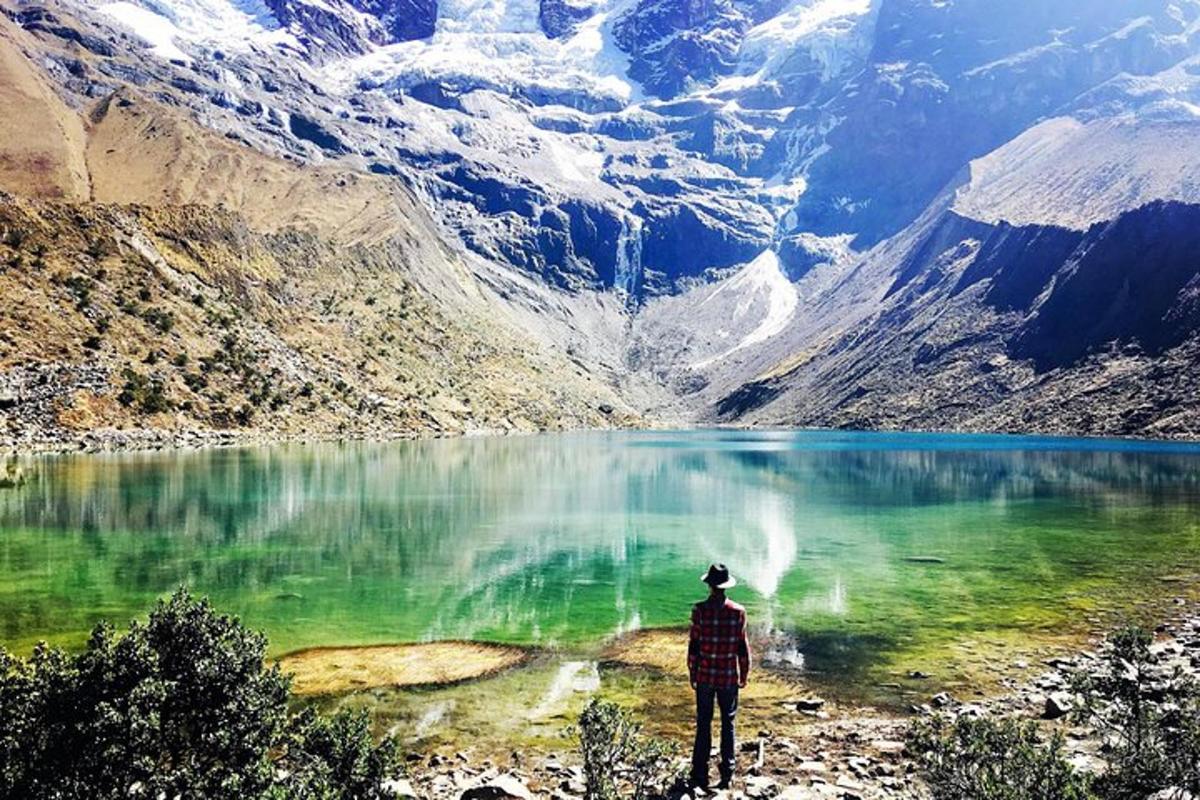 Un hombre parado frente a un lago de montaña