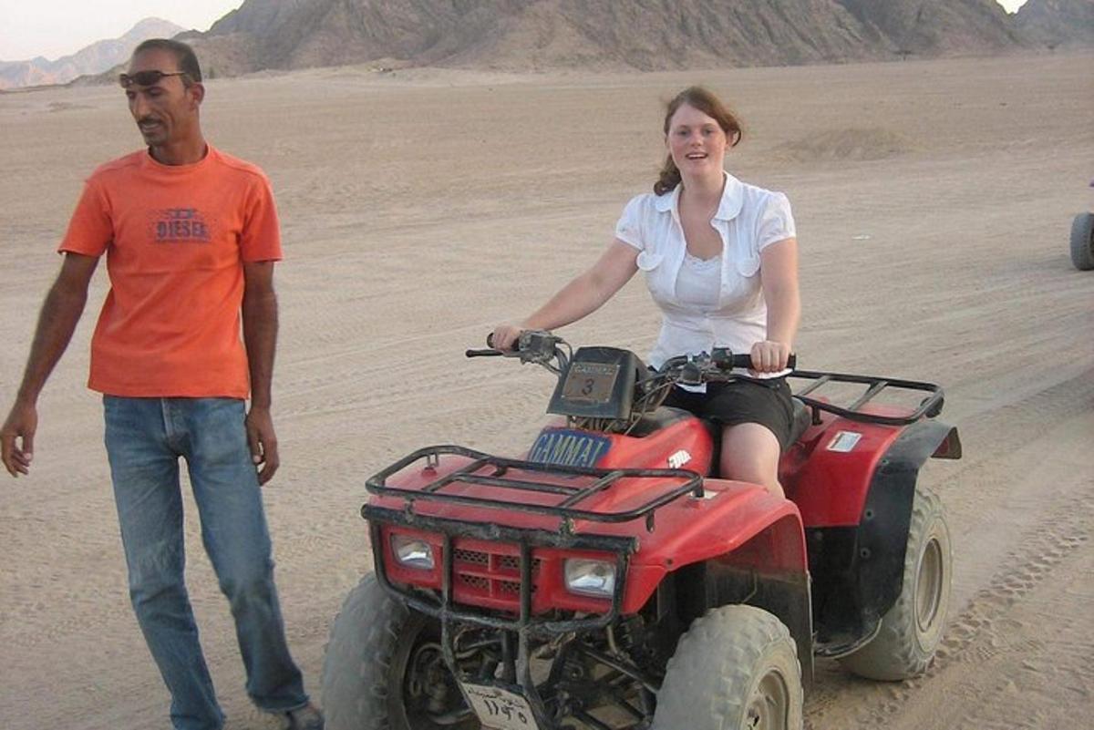 Un hombre y una mujer en un vehículo con ruedas en el desierto