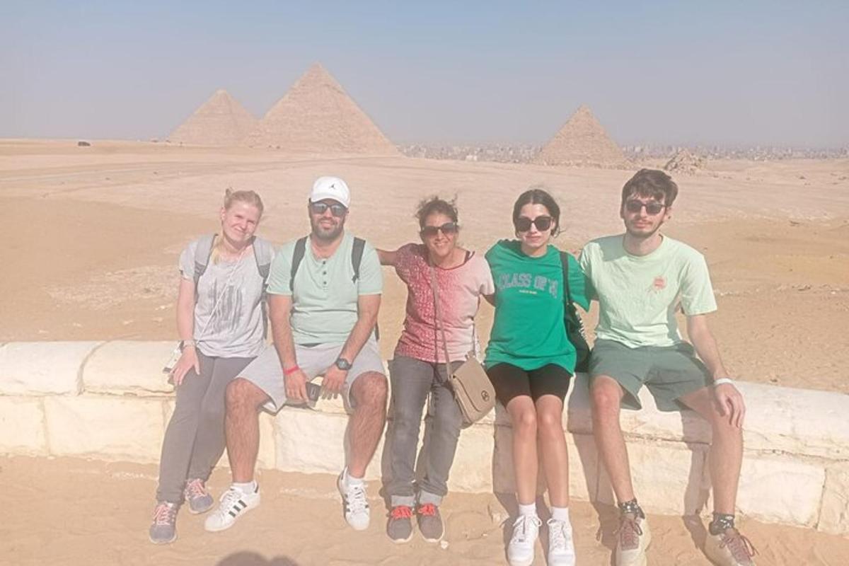 un gruppo di persone sedute su un muro di fronte alle piramidi