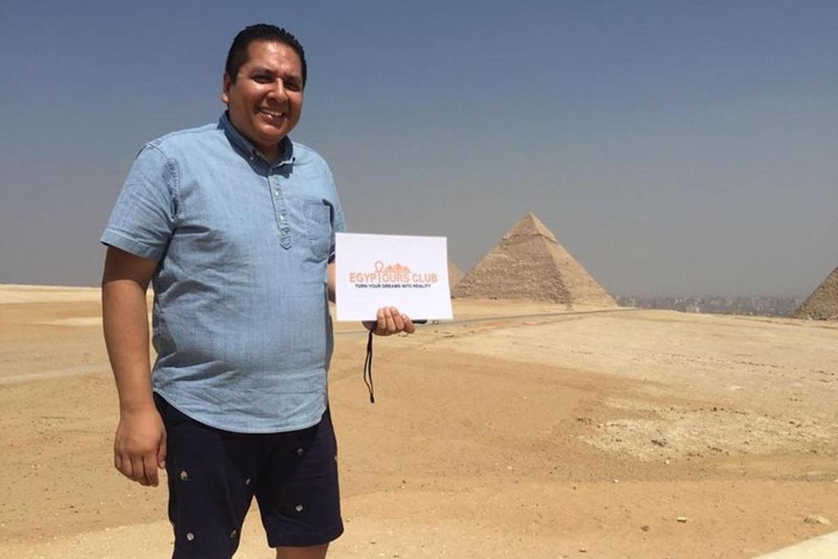 a man holding a sign in front of the pyramids