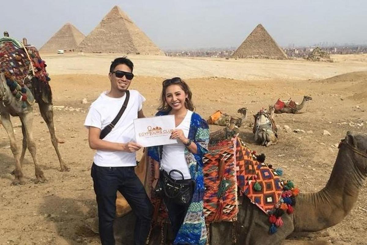 Egy férfi és egy nő egy táblát tartanak a piramisok előtt