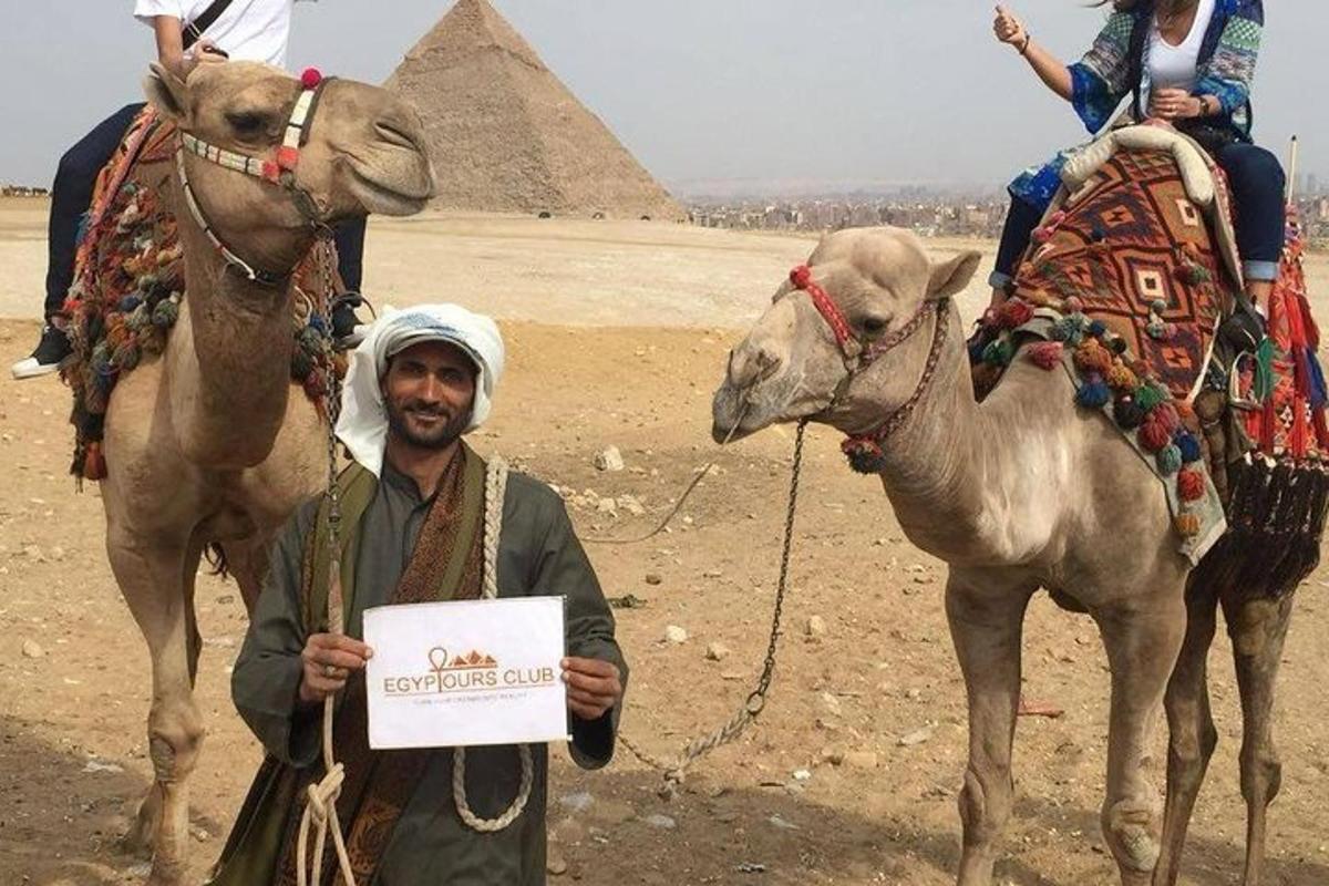 a man holding a sign next to a camel and the pyramids