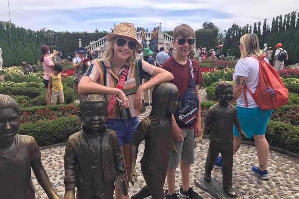 a group of people standing next to statues in a garden