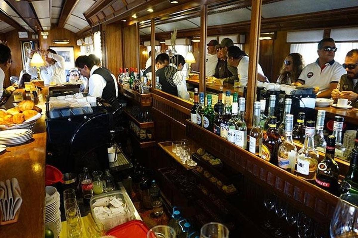 skupina lidí stojících kolem baru s lahvemi alkoholu