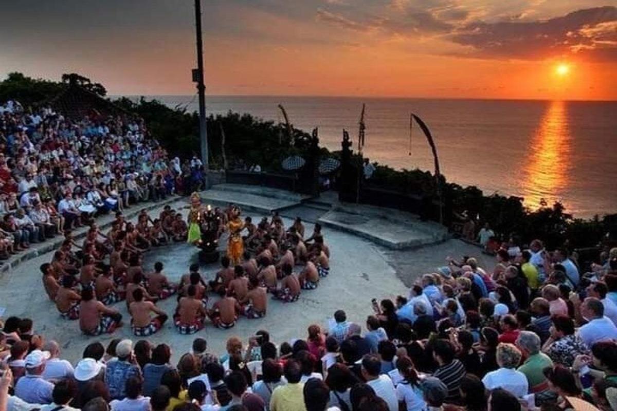 a large crowd of people watching a concert in front of the ocean