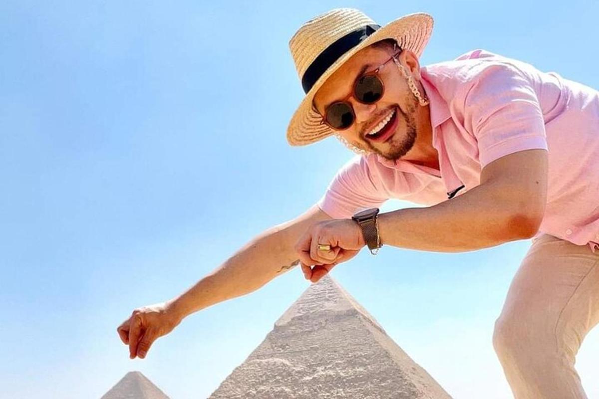 mees, kes kannab mütsi ja päikeseprille, seisab püramiidi ees