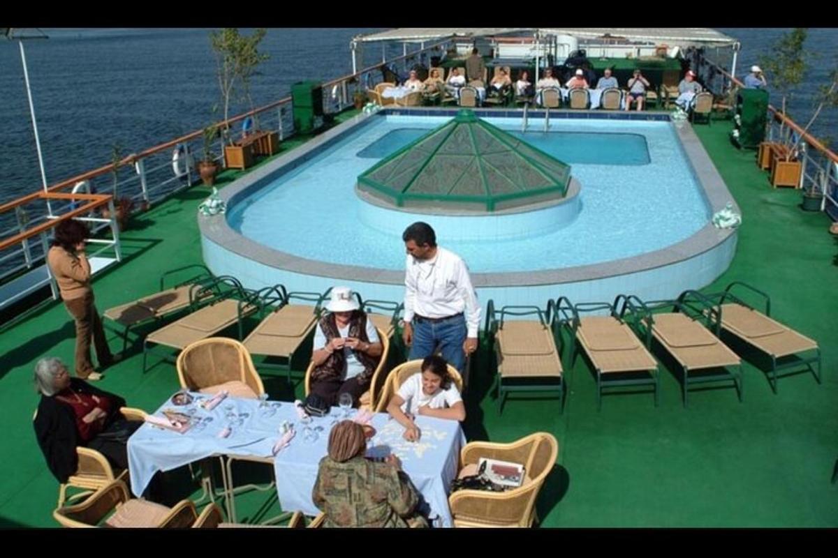 a group of people sitting around a table in front of a swimming pool