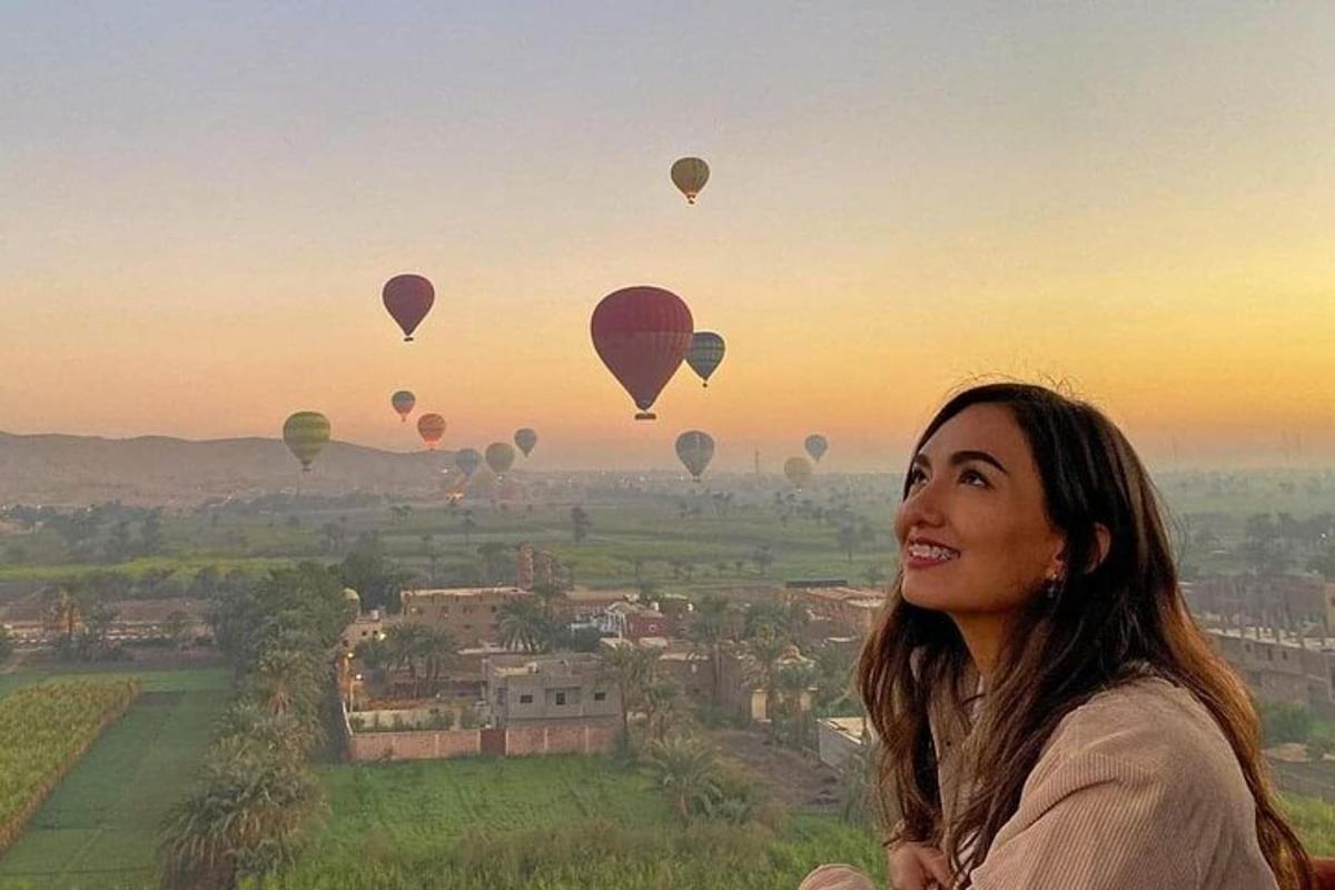 a woman standing on top of a hill with hot air balloons