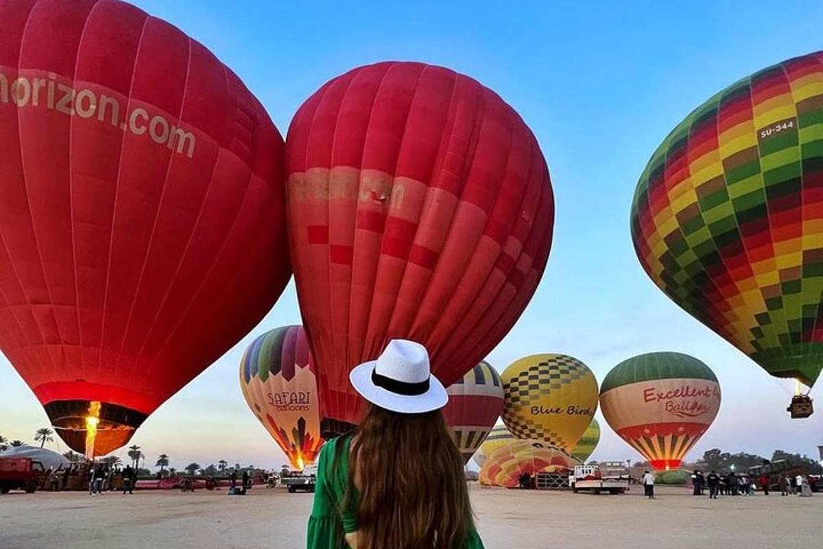 una dona amb barret mirant un munt de globus aerostàtics