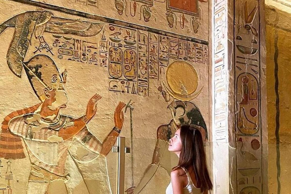 Una mujer parada frente a una pared con un mural.