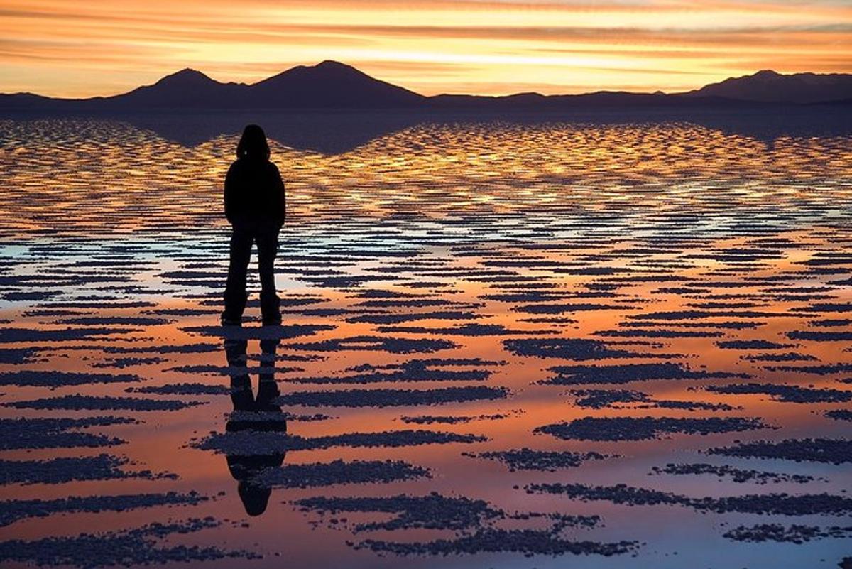 une personne debout sur la plage au coucher du soleil