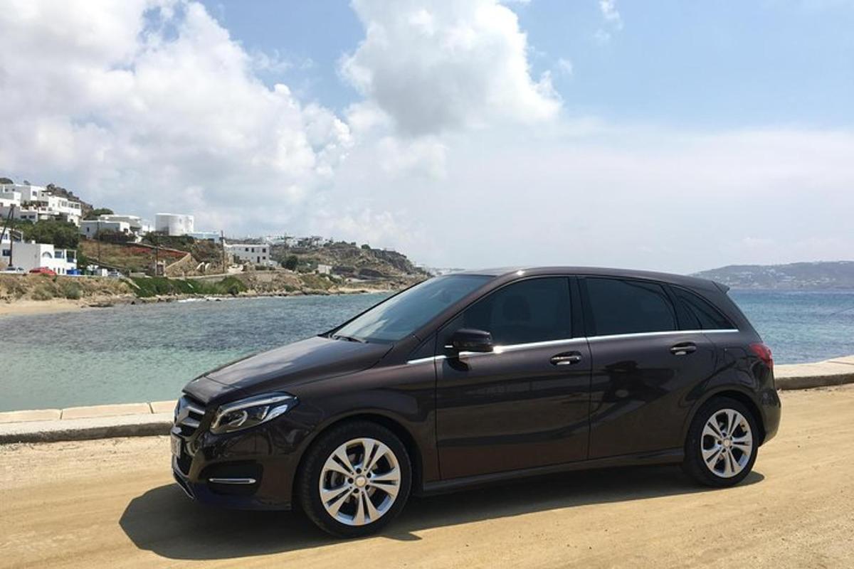Un coche negro aparcado en una playa cerca del agua.