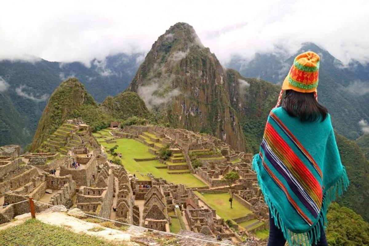 Una mujer parada en la cima de una montaña mirando una ciudad.