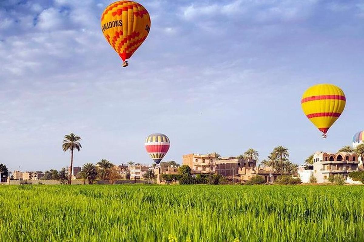 tiga belon udara panas terbang di atas padang hijau