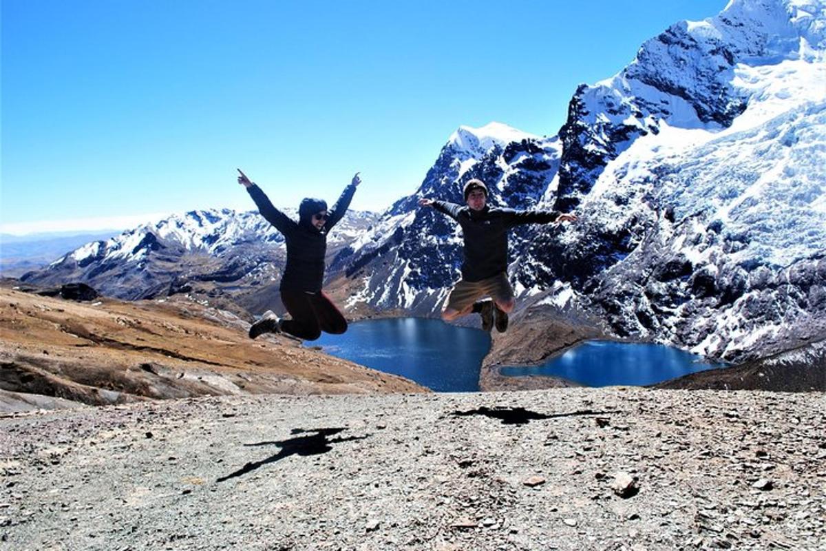 Dos personas saltando en el aire frente a una montaña.