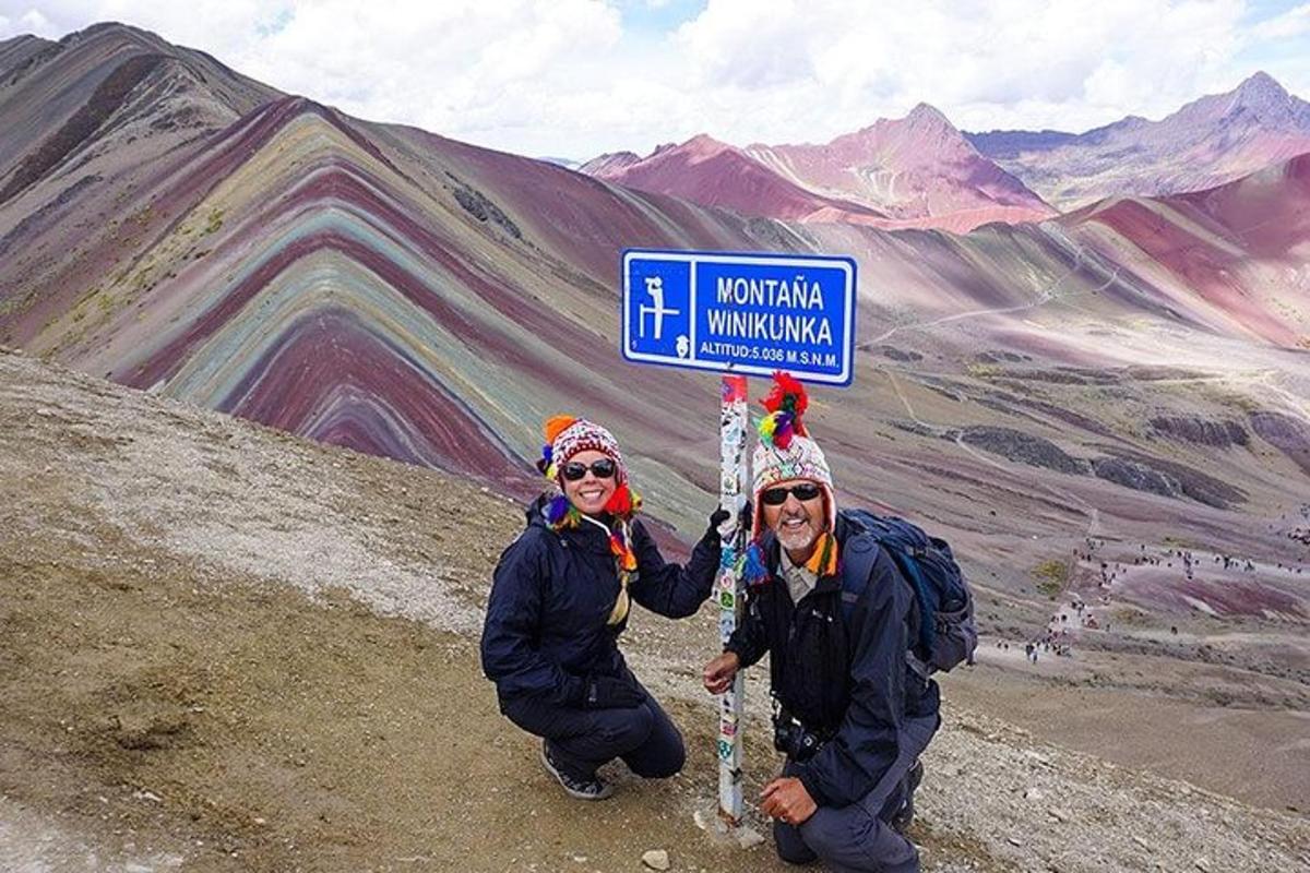 Dos personas de pie junto a un cartel en una montaña.