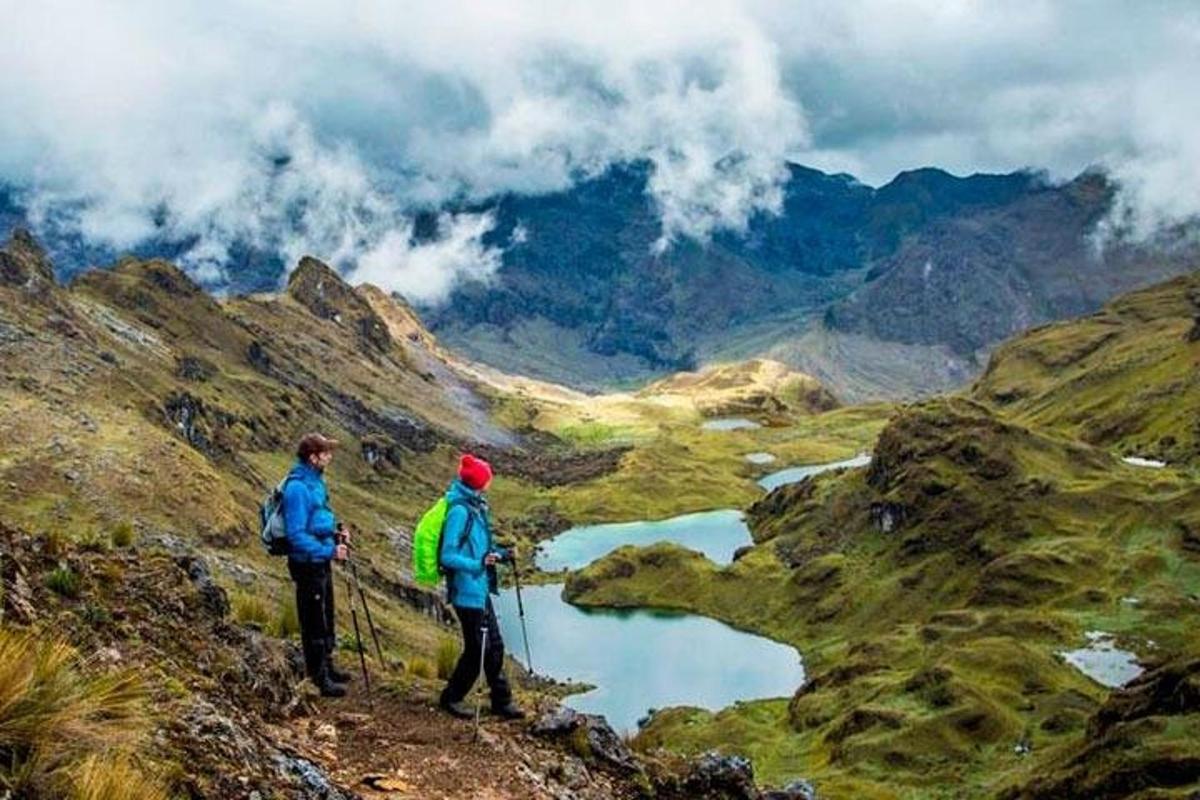 duas pessoas em pé no topo de uma montanha com vista para um vale