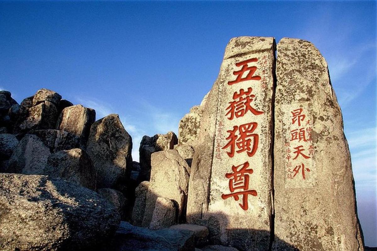 a rock with chinese writing on it next to some rocks