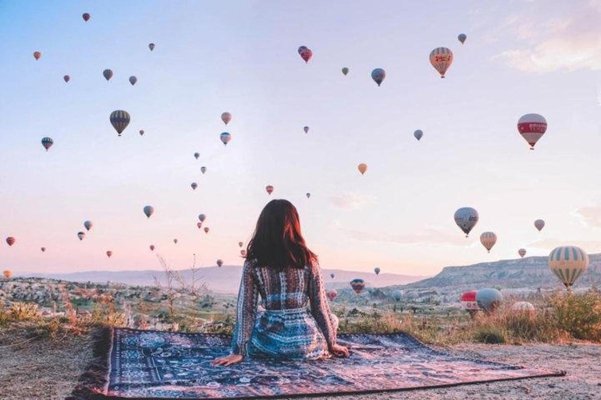 seorang wanita duduk di atas karpet sambil memandangi balon udara