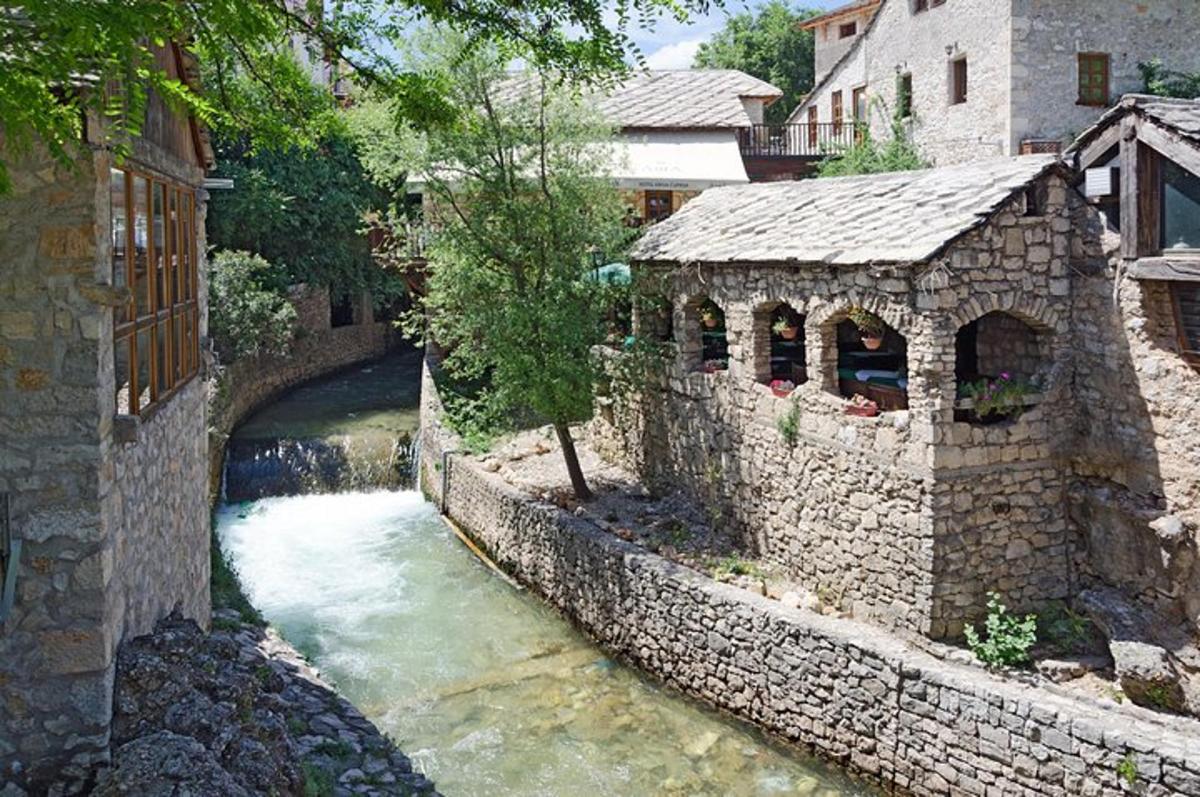un pont de pedra sobre un riu al costat d'un edifici