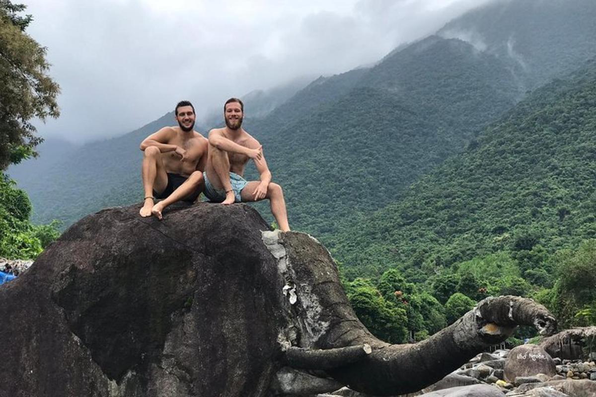 Dos hombres sentados en la cima de una roca con un elefante.