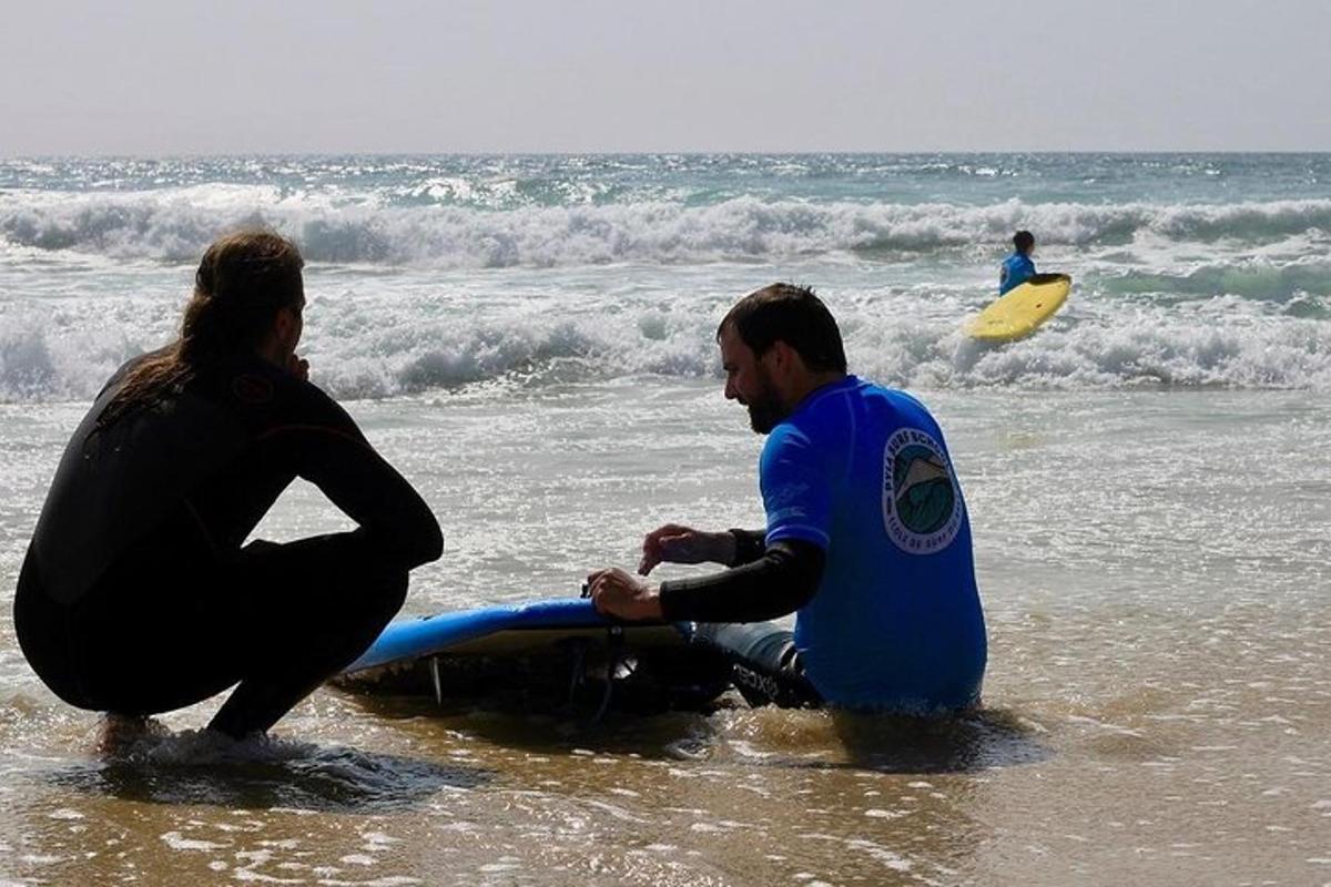 two people sitting in the ocean with a surfboard