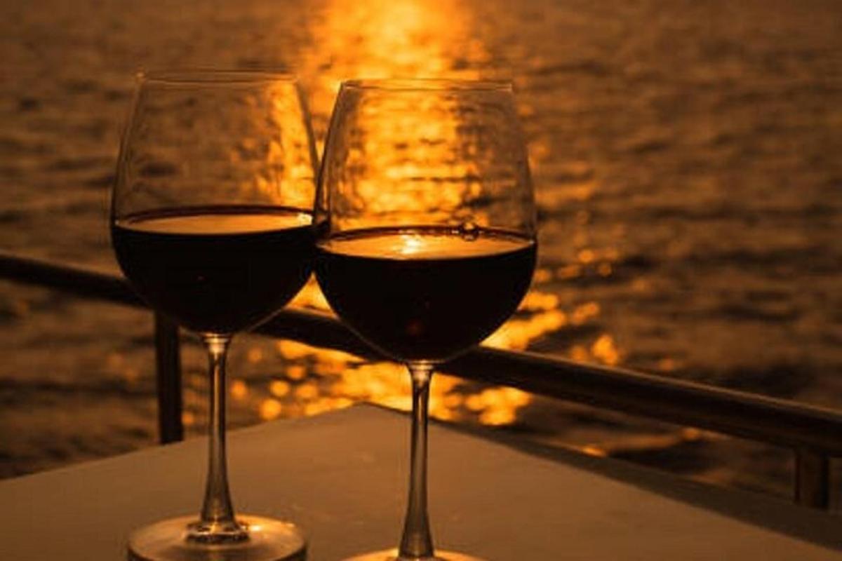 Dos copas de vino sentadas en una mesa cerca del agua.