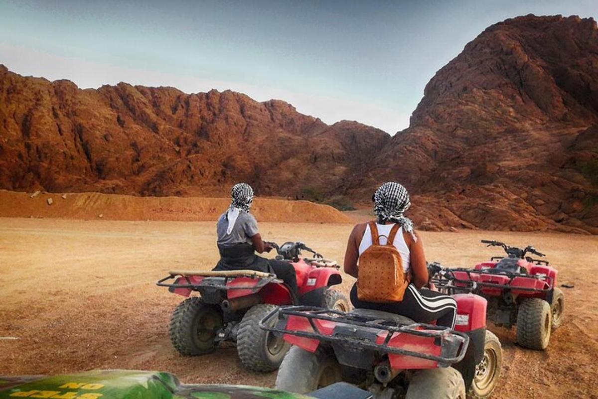 twee mensen rijden op quads in de woestijn