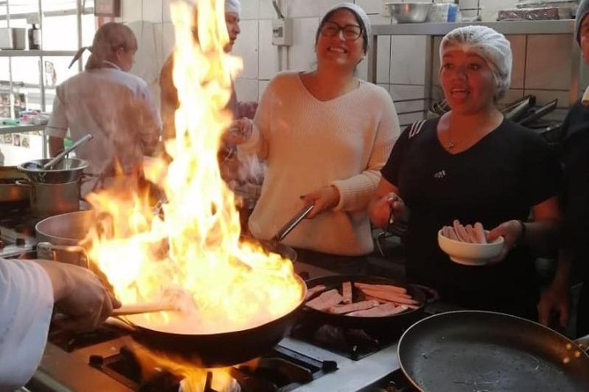 skupina lidí vařících jídlo na pánvi s plameny