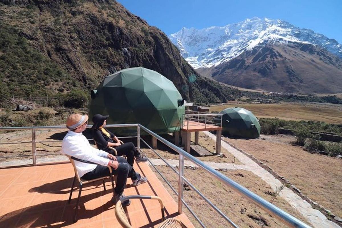 two people sitting on a deck with a view of a mountain