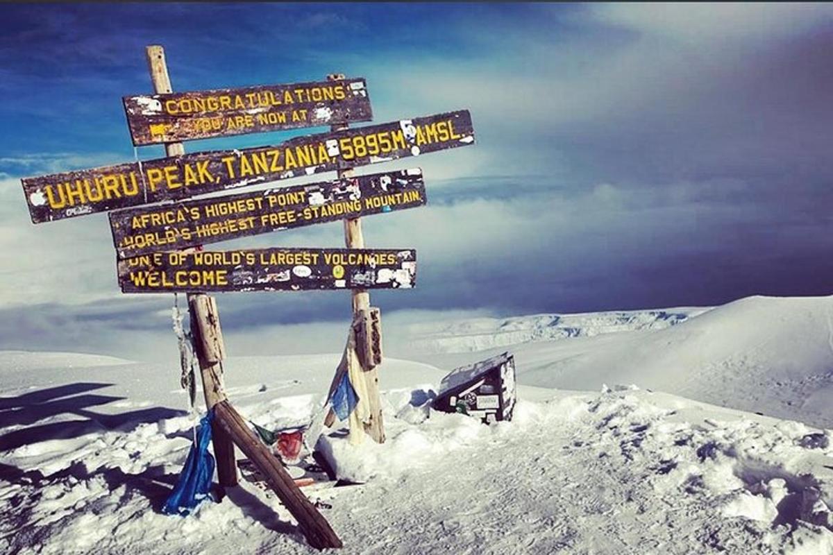 uma placa direcional no topo de uma montanha coberta de neve