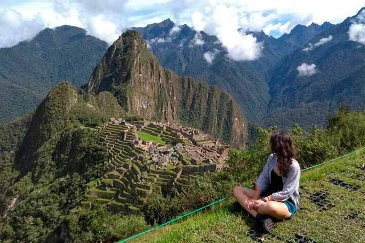 seorang wanita duduk di atas bukit sambil memandangi sebuah desa di pegunungan