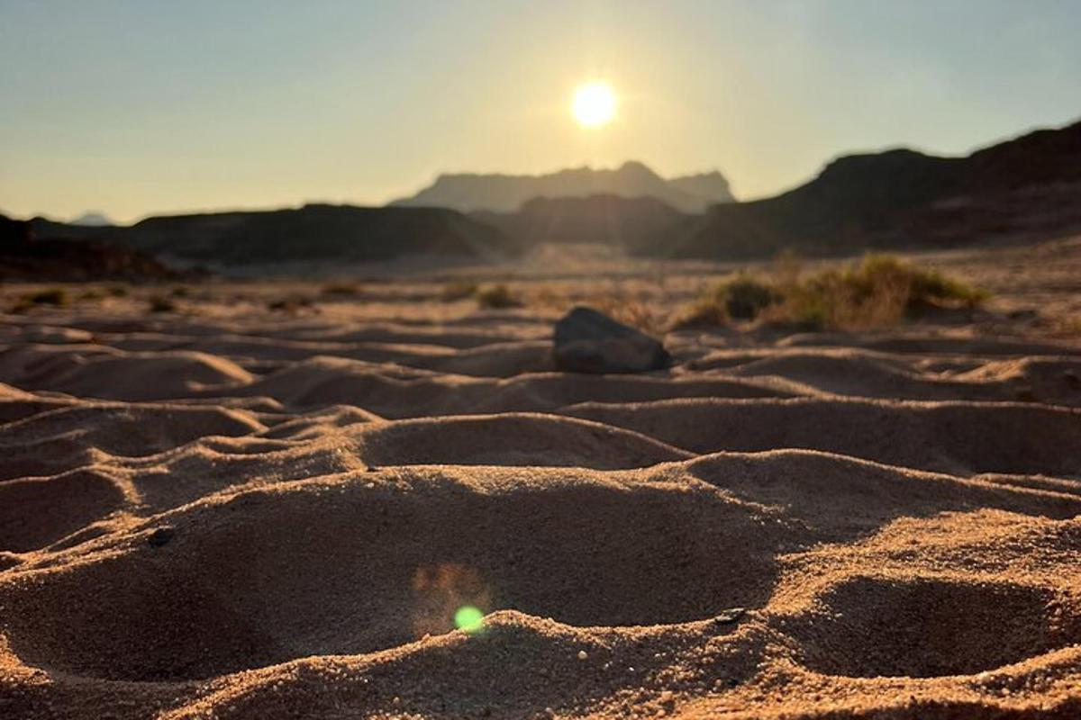um deserto com o sol se pondo no horizonte