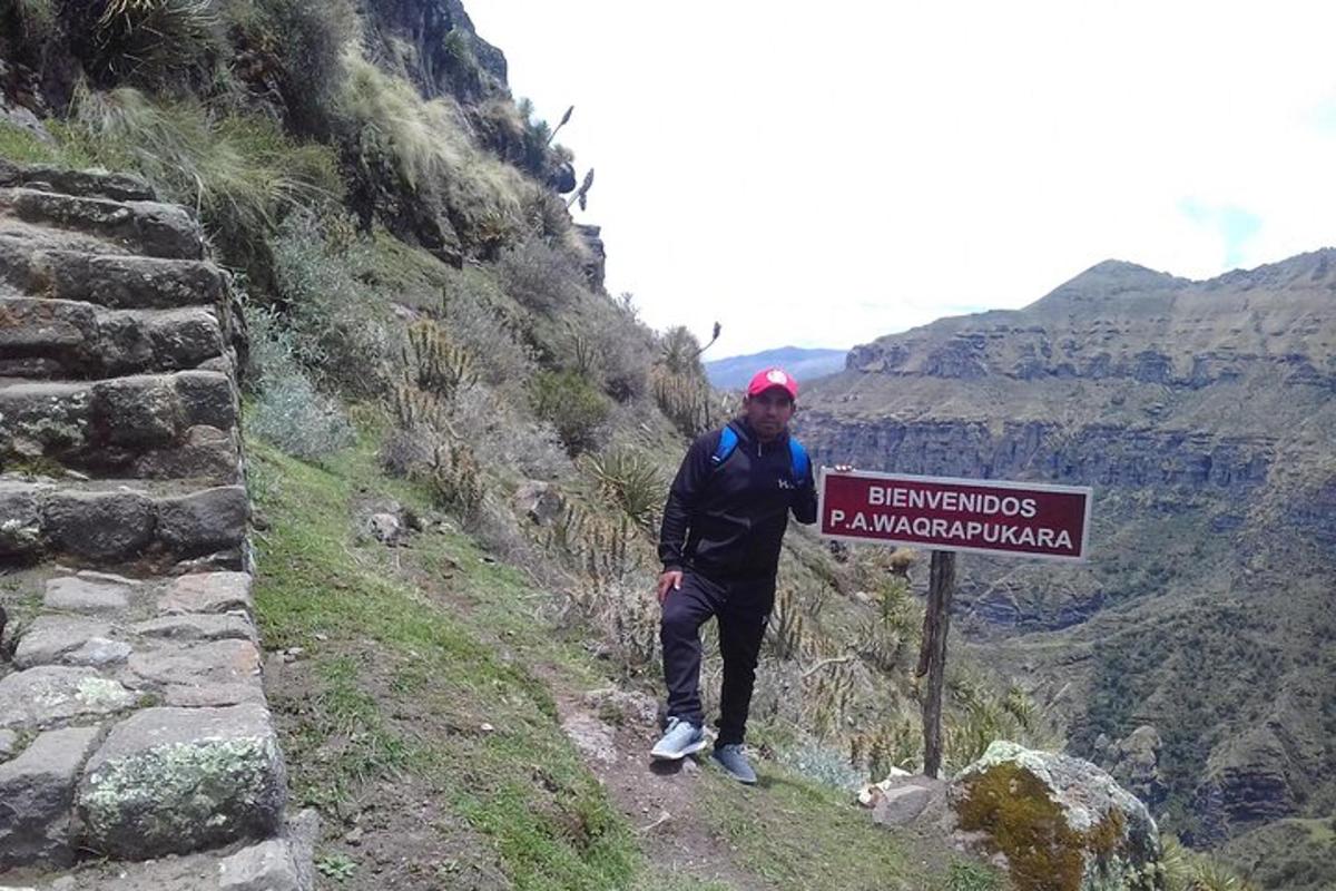 seorang lelaki berdiri di sebelah papan tanda di atas gunung
