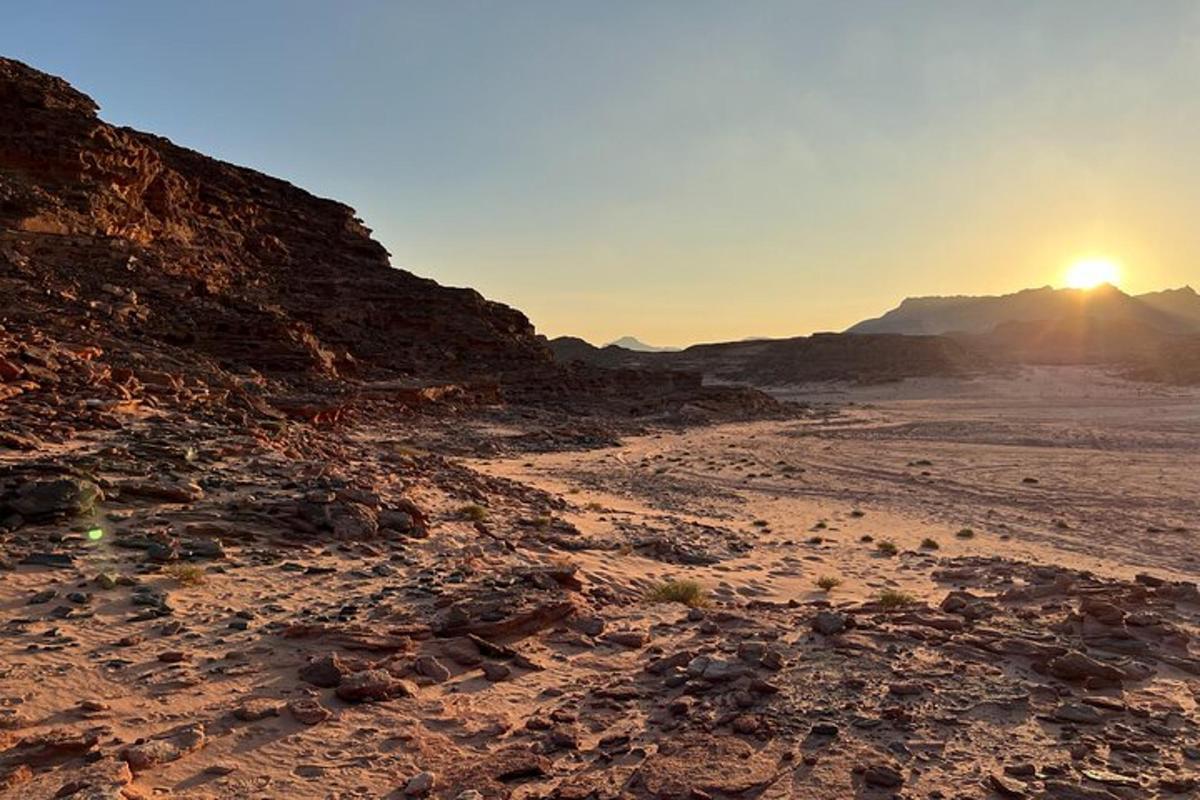 uma cena de deserto com o sol se pondo à distância