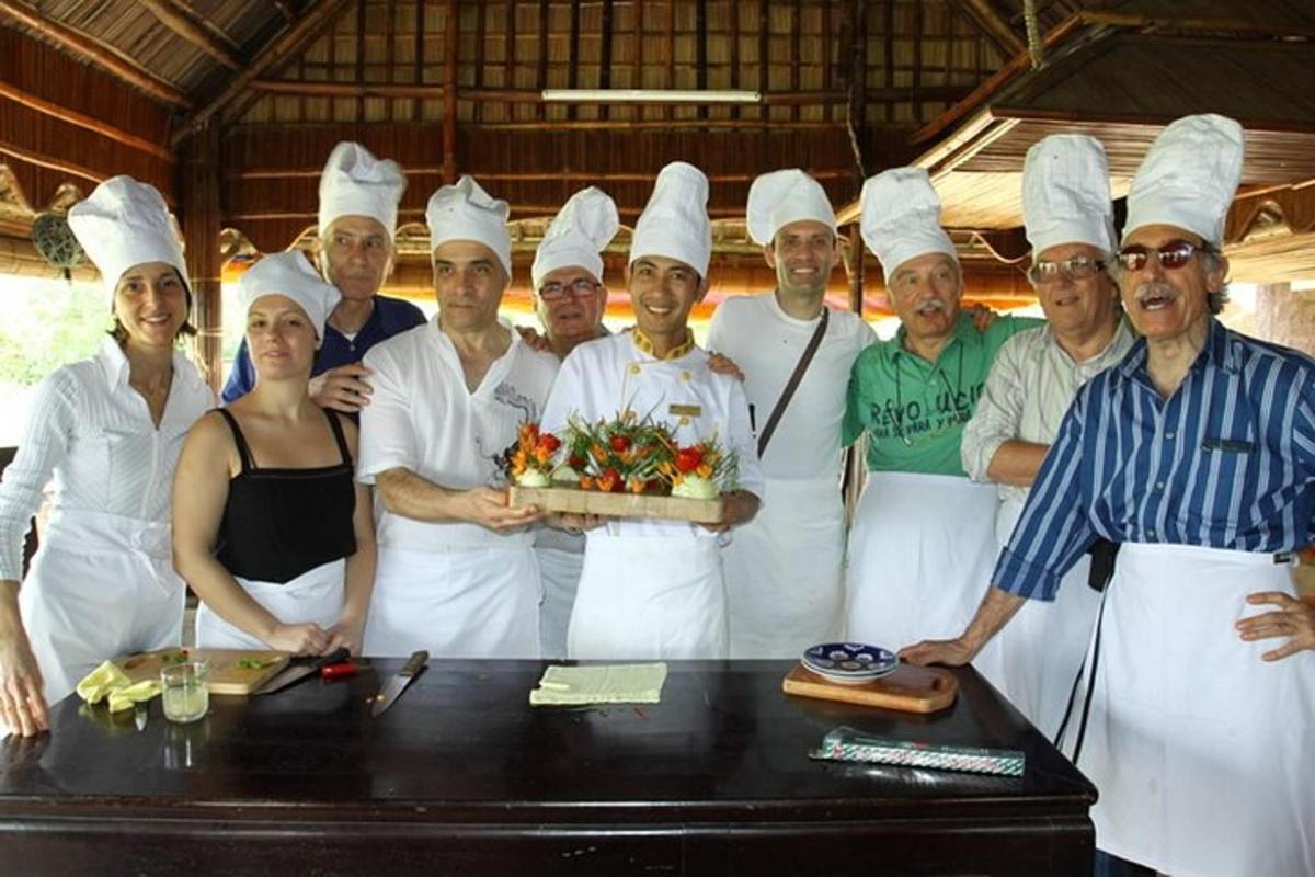um grupo de chefs em pé ao redor de uma mesa com um bolo