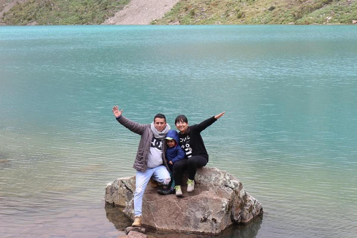 tres persones assegudes en una roca a l'aigua