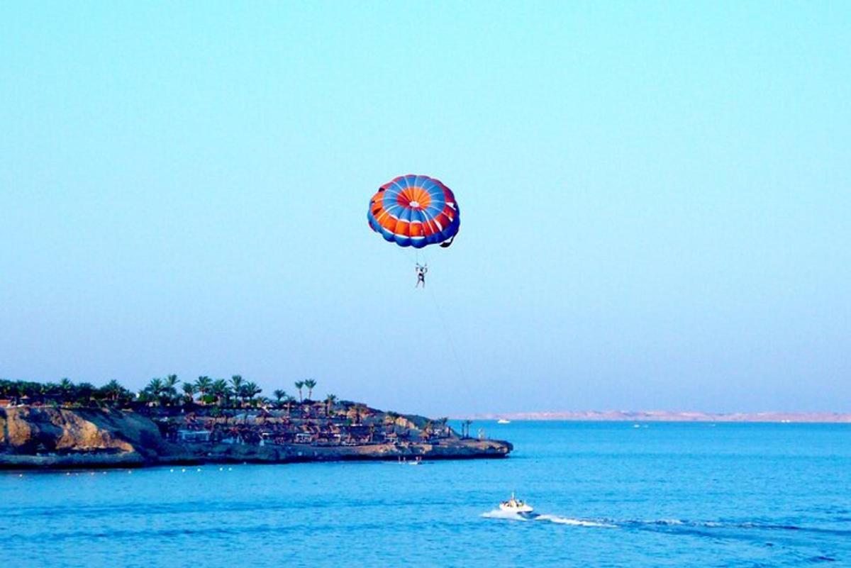 a blue and red parachute flying over the water