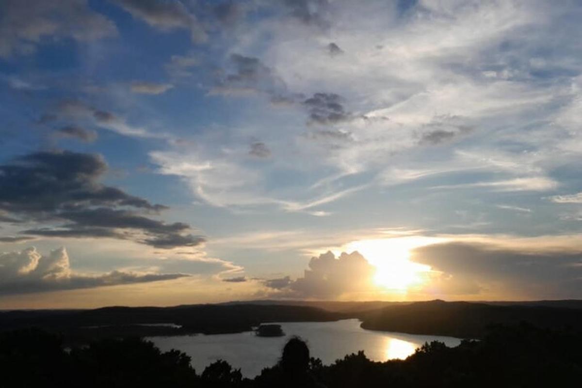 a sunset over a lake with the sun in the sky