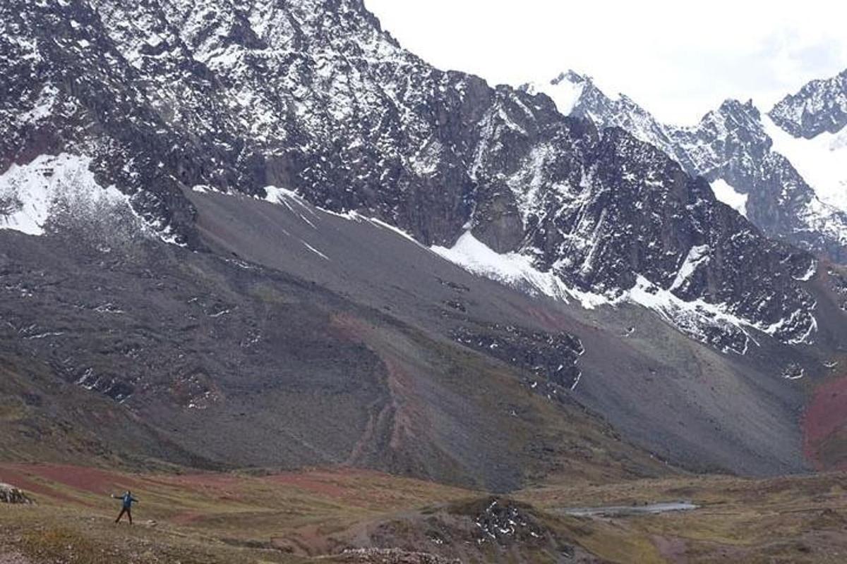 una persona parada en una colina frente a una montaña